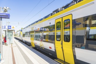 Modern yellow train on a sunny platform with blue sky, battery Electric train with green