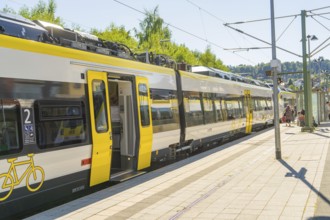 Modern yellow train on the platform on a sunny day, battery Electric train with green electricity,