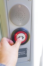 Close-up of a hand pressing a red illuminated stop button, battery Electric train with green