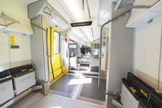 Modern and brightly lit train area with yellow doors and railings, battery Electric train with