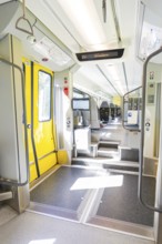 Modern entrance in the train with yellow doors and brightly lit interior, battery Electric train