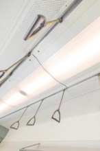 Ceiling view with lighting and grab handles in a modern vehicle, battery Electric train with green