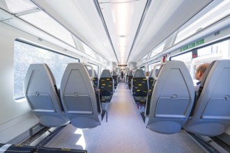 Spacious and modern train compartments with rows of window seats, battery Electric train with green