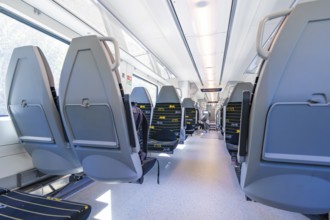 Modern train interior with rows of seats along large windows, battery Electric train with green