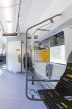 Train compartment with poster on the wall and empty seats in daylight, battery Electric train with