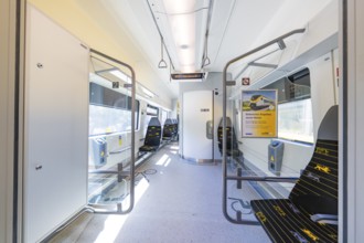 Modern interior of a train with blue seats and plenty of daylight, battery Electric train with