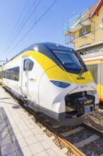 Yellow and white modern train on a sunlit platform, battery Electric train with green electricity,