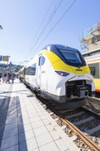 Modern train in yellow and white colour scheme on the platform under a blue sky, battery Electric