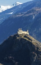 The ruins of Tourbillon Castle sit enthroned on a hill in front of the snow-capped mountains of the