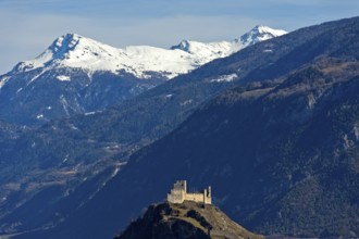 The ruins of Tourbillon Castle sit enthroned on a hill in front of the snow-capped mountains of the
