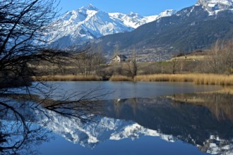 The snow-covered Haut de Cry mountain range is reflected in the Mont d'Orge lake, Lac de Mont