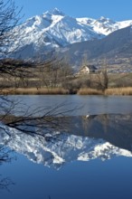 The snow-covered Haut de Cry mountain range is reflected in the Mont d'Orge lake, Lac de Mont