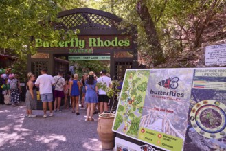Entrance to a nature park full of butterflies with visitors and park sign, Butterfly Valley,