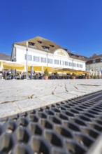 A café with yellow parasols in a cobbled street under a blue sky, Lake Constance, Germany