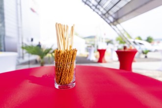 A jar of breadsticks stands on a red table at an outdoor event, Lake Constance, Germany