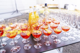 Many cocktail glasses with orange-coloured drink on a table at an outdoor party, Lake Constance,