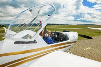 Pilot and passenger co-pilot preparing for take-off in cockpit of two-seater touring motor glider
