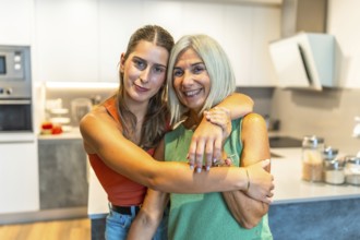 Young woman hugging her smiling mother in a bright modern kitchen, showing their loving bond and