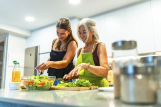 Two women in a modern kitchen joyfully preparing a fresh salad together, highlighting the bond and