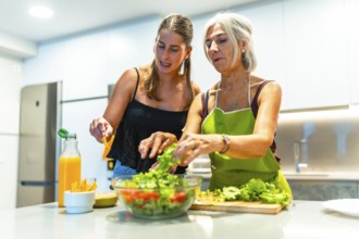Mother and daughter preparing a mixed salad with lettuce, tomato, and orange juice in a modern