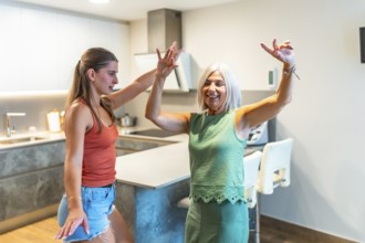 Energetic mother and daughter enjoying a lively dance in a modern kitchen, showcasing family