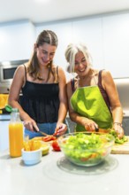 Smiling mother and daughter preparing a fresh salad together in a modern kitchen, highlighting