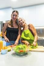 Two women happily preparing a fresh salad in a brightly lit kitchen, showcasing the joy of cooking