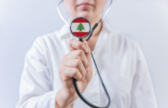 Female doctor holding stethoscope with Lebanon flag. National health system of Lebanon