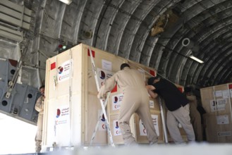 Members of the Qatari Air Force unload humanitarian aid supplies from a transport aircraft at