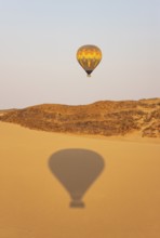 The hot-air balloon above an arid plain and isolated mountain ridges at the edge of the Namib