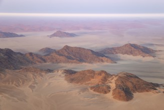Arid plains and isolated mountain ridges at the edge of the Namib Desert. Early morning. Aerial