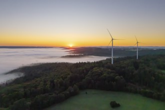 Wind turbines at sunrise over a misty forest landscape, near Schorndorf, Rems-Murr district,