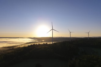 A wind turbine stands prominently in the morning fog under a clear sky, near Schorndorf, Remstal,