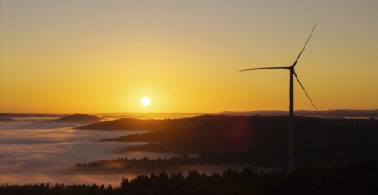 Wind turbine in front of a picturesque sunrise over a misty landscape, near Schorndorf, Remstal,