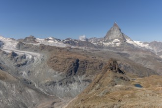 The towering peak of the Matterhorn dominates the clear sky, surrounded by rocky terrain and