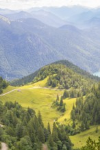View over green hills and forests with mountain ranges in the background, Herzogstand summit,
