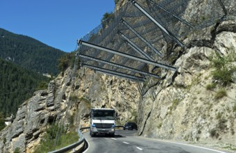 Motor vehicles travelling under safety nets on the rockfall-prone road Les Pontis, Val d'Anniviers,