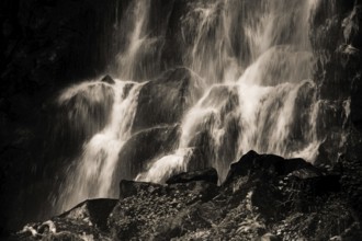 Vaucoux waterfall cascades gracefully over dark rocks, surrounded by lush greenery, Auvergne