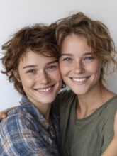 Two smiling woman in casual clothes pose friendly on a wall, symbolic image for same-sex