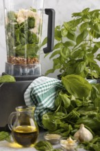 Blender with basil, parmesan and sunflower seeds alongside other ingredients for pesto