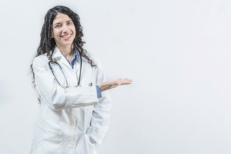 Smiling young female doctor showing empty space isolated. Female latin doctor showing a product