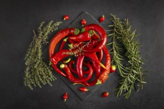 Hot red peppers and herbs, rosemary and thyme, on a dark background