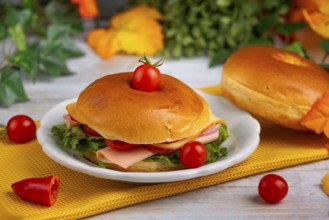 An autumnally decorated table with a filled bagel and colourful leaves