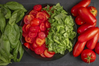 Sliced tomatoes and basil on a black plate