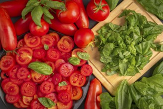 Fresh tomatoes and basil leaves on a chopping board, in bright red and green colours
