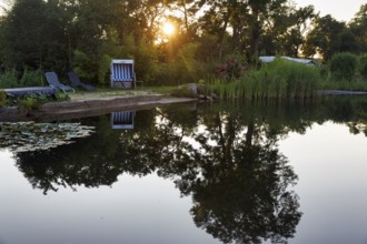Idyllic swimming pond with beach chair and deckchairs, campsite, rays of sunshine in the evening,
