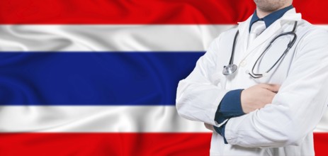 Thailand healthcare concept. Male doctor on Thailand flag. Doctor with crossed arms on Thailand