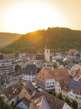 Historic old town with church tower and surrounding hills in the golden evening light, small town