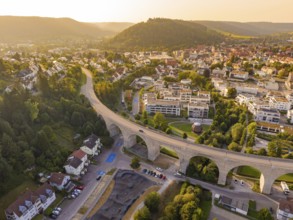 Aerial view of a town with viaduct and surrounding hills in warm sunlight, small town Perle Nagold,