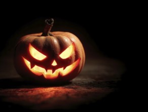 A spooky carved glowing pumpkin in a dark room, symbolising Halloween and autumnal mood, AI